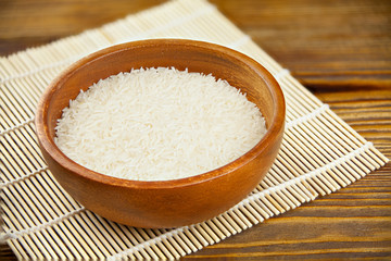 Fototapeta na wymiar Raw white rice in bowl on wooden background