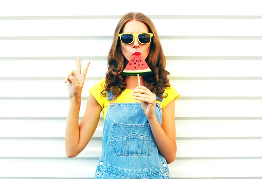 Fashion cool girl eating a slice of watermelon in the form of ice cream on a white background