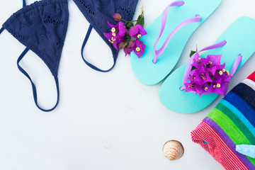 Summer beach fun - sandals with swimming suit, beach towel close up , copy space on white wooden backgroun