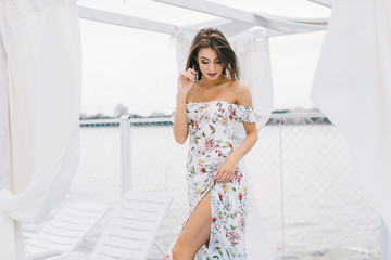 Portrait of a beautiful woman in a dress posing on a white wooden beach of summer.