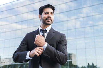Successful businessman or worker standing in suit and straightens shirt