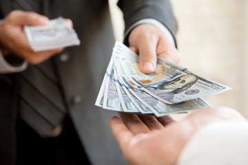 Businessman giving money to a man, US dollar bills