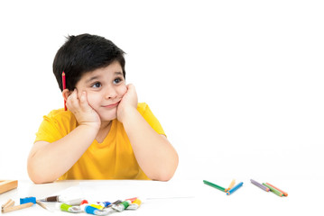 Cute little boy imagining with hands on cheeks