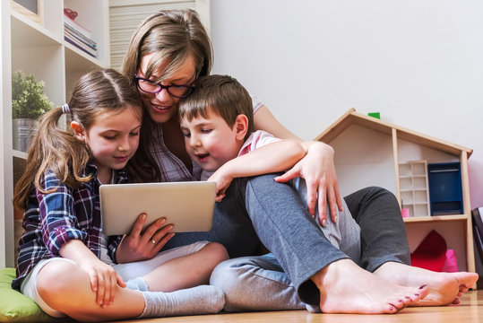 Mother with two children using digital tablet at home