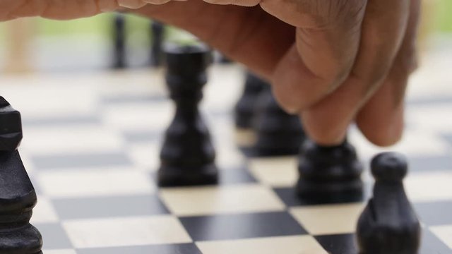 Close up of hand moving a chess piece to win a checkmate