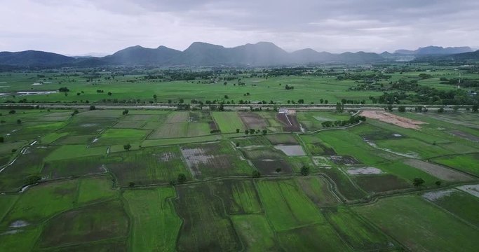 aerial view of Picturesque countryside landscape panorama with view of green field and mountains on rainy day in Thailand