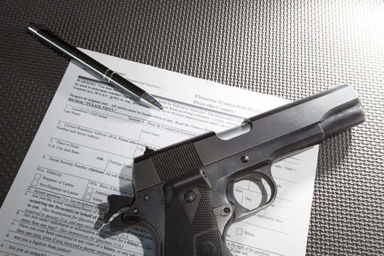 Semi-auto pistol chambered in .45 with the 4473 ATF background check transfer paperwork underneath and a pen