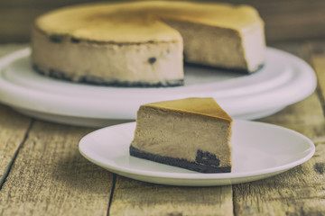 Homemade chocolate cheesecake on rustic wood table.Baked chocolate cheesecake on plate. Brownie cheesecake for coffee break or tea time in cafe. Triangle slice piece of chocolate cake vintage style.