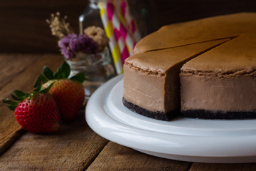 Homemade chocolate cheesecake on rustic wood table.Baked chocolate cheesecake on plate. Brownie cheesecake for coffee break or tea time in cafe. Triangle slice piece of chocolate cake.