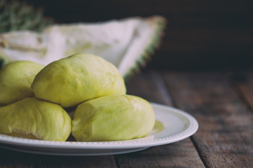 Traditional Thai fruit :Durian,the king of fruit in Thailand on white plate put on rustic wood table. Durian is tropical fruit so delicious, sweet and good smell. Ripe durian has yellow gold colour.