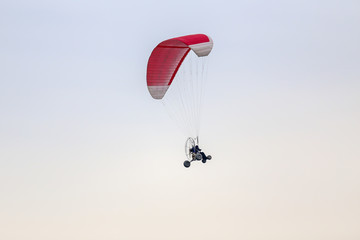 red and white paramotor fly on the sky.
