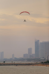 scenic view of people on the beach with paramotor and city tower on the background. with sunset light on the evening.