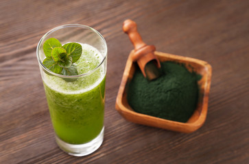 Green smoothie with spirulina on wood background
