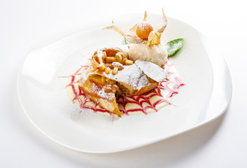 Apple Strudel with vanilla ice cream, berry sauce, mint and physalis isolated on white background. 