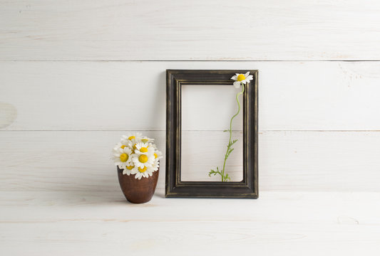 Daisy bouquet in clay vase and photo frame