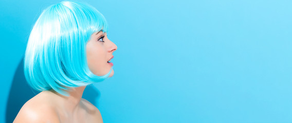 Beautiful woman in a bright blue wig on a blue background