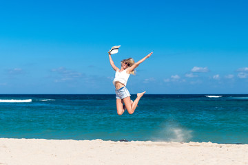 Freedom concept. Sexy woman on a beach of Bali island. She is enjoying serene ocean nature during travel holidays vacation outdoors. Jumping.