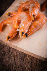 Frozen shrimp with ice cubes on a wood background