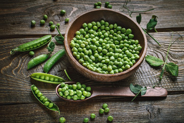 Delicious ripe green peas lying on a wooden table.