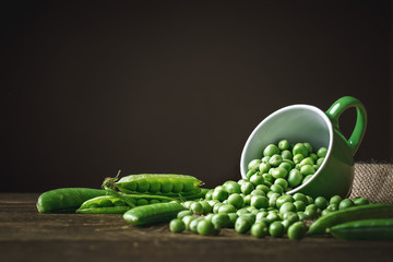 Delicious ripe green peas lying on a wooden table.