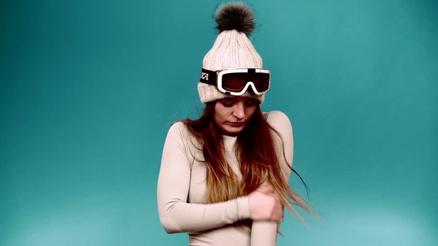 Frozen woman fit female wearing goggles thermal underwear long sleeves top apparel for skiing training. Girl feel cold. Clothing fashion sport wear concept, on blue studio shot, full HD.