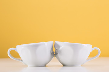 Two white cups on a yellow background. I love uou.