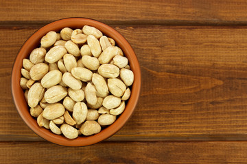 Roasted salted peanuts in bowl on a wooden background