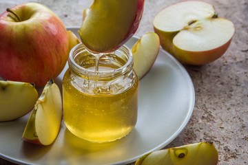 Organic honey in glass jar and red apple on the plate