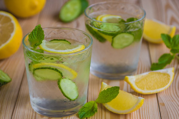 Detox water, fresh organic lemonade with ice, cucumber, lemon and mint on wooden background