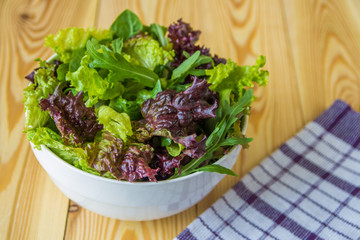 Salad leaves, purple lettuce, spinach, arugula. Mixed fresh salad in a white bowl