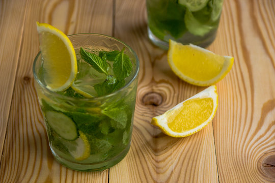 Detox water, fresh organic lemonade with ice, cucumber, lemon and mint on wooden background