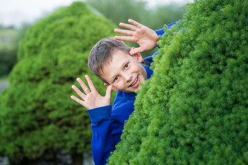 Boy teenager peeking out of a bush