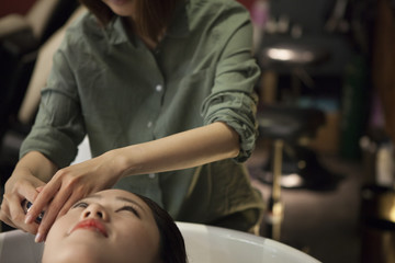 Hairdresser is rinsing customer's hair