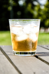 Cold drink with ice cubes on a wooden terrace table