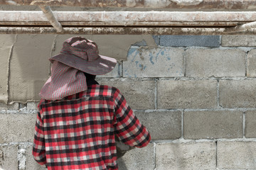 Man pressing an cement tile into a glue on a wall.