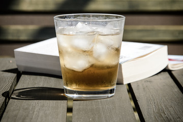 Cold drink with ice cubes on a wooden terrace table