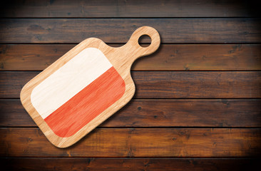 Concept of Polish cuisine. Cutting board with a Poland flag on a wooden background