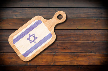 Concept of Israeli cuisine. Cutting board with a Israel flag on a wooden background