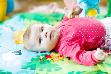Cute adorable newborn baby playing on colorful toy gym