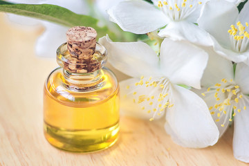 Essential oil in glass bottle with fresh jasmine flowers, beauty treatment. Spa concept Selective focus. Fragrant oil of jasmine flowers macro wooden table horizontal. Herbs have medicinal properties.