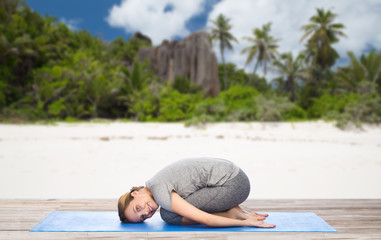 Fototapeta premium happy woman doing yoga in child pose on beach