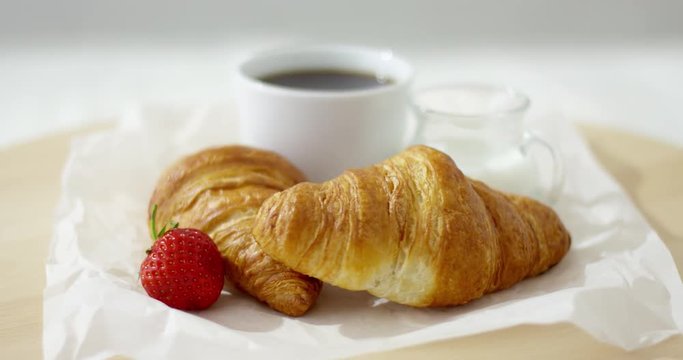 Close-up shot of freshly baked croissants served with cup of coffee and strawberry. 