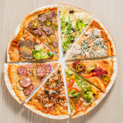 Compound pizza from slices of different pizzas on a wooden background