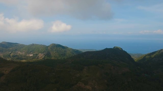 Mountains with rainforest covered with green vegetation and trees on the tropical island, landscape. Aerial view: Mountains and hills with wild forest, sky clouds. Hillside rainforest and jungle