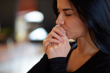 close up of unhappy woman praying god at funeral