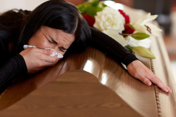 woman with coffin crying at funeral in church - obrazy, fototapety, plakaty