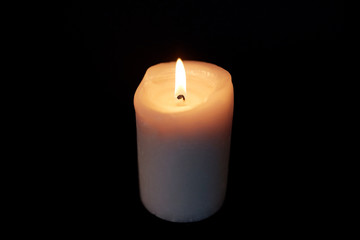 Fototapeta na wymiar candle burning in darkness over black background
