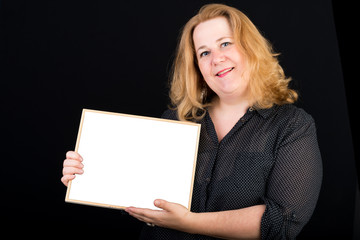 Naklejka premium Beautiful light overweighted european red haired adult carrying a white blank board in front of a black background - studio shot