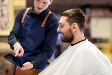 Obraz premium barber showing tablet pc to man at barbershop