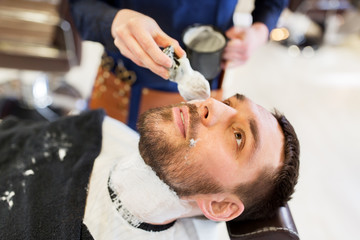 man and barber applying shaving foam to beard